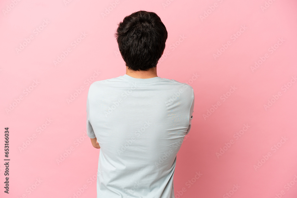 Young Russian man isolated on pink background in back position Young Russian man isolated on pink background in back position