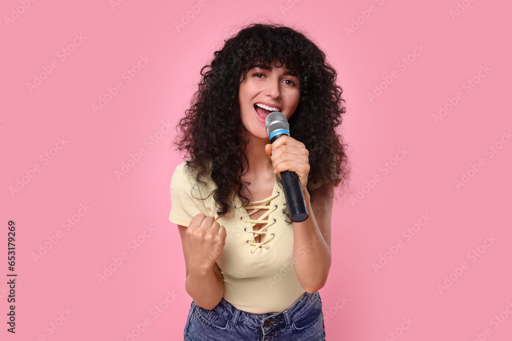 Beautiful young woman with microphone singing on pink background Beautiful young woman with microphone singing on pink background