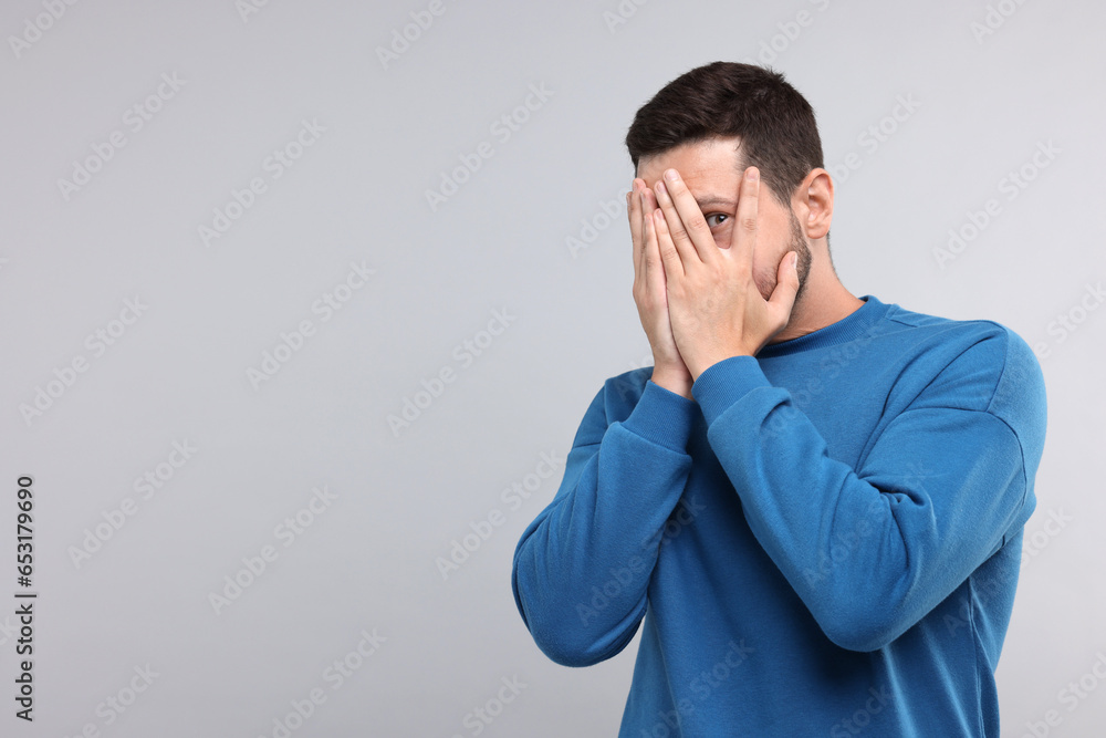 Embarrassed man covering face on light grey background. Space for text Embarrassed man covering face on light grey background. Space for text