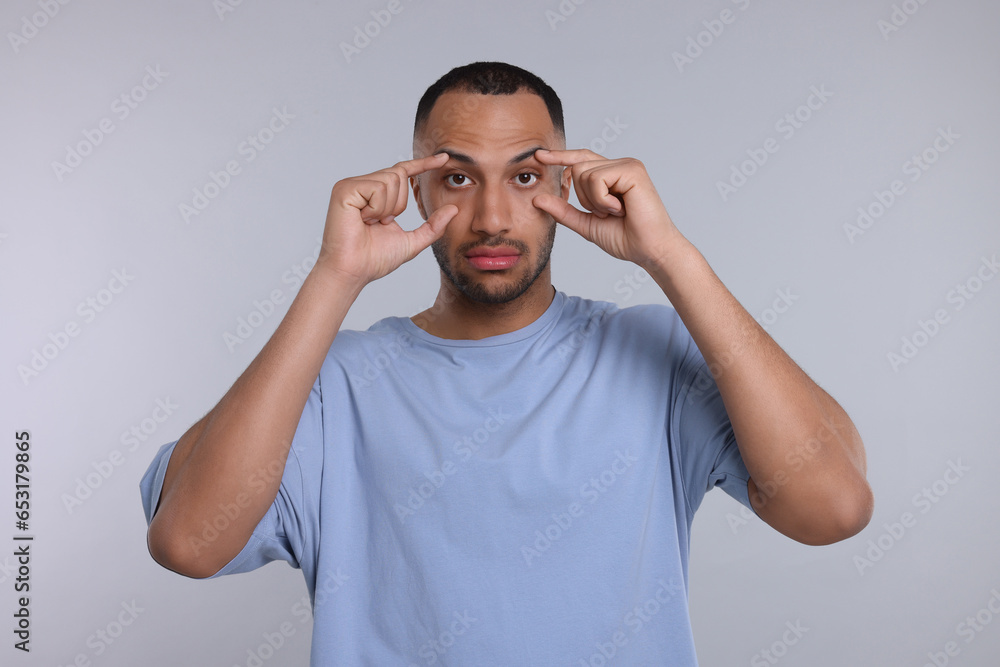 Fototapeta premium Tired man on light grey background. Insomnia problem
