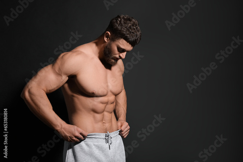 Handsome muscular man on black background, space for text. Sexy body