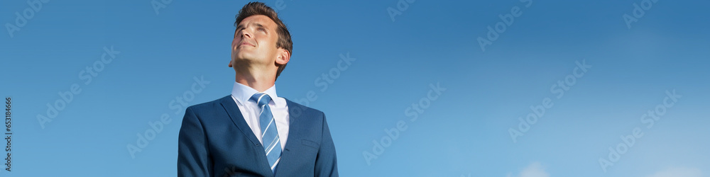 A contented businessman in formal attire highlighting a blank ad area on a tranquil blue background A contented businessman in formal attire highlighting a blank ad area on a tranquil blue background