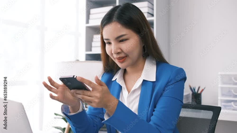 Female entrepreneur businesswoman, successful Asian business woman using smartphone, cellphone application, online communication, sitting at table in office indoors. Female entrepreneur businesswoman, successful Asian business woman using smartphone, cellphone application, online communication, sitting at table in office indoors.
