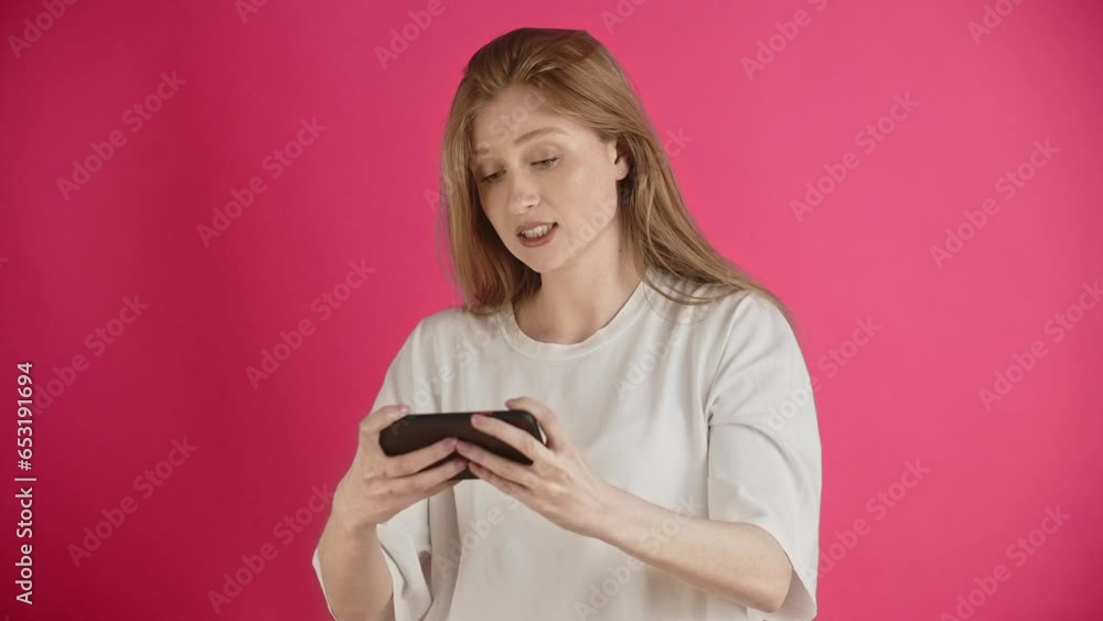The girl grimaces and tries to adjust the joystick with a stucked button. Young woman emotionally, expressively and zealously, but unsuccessfully trying to complete the game. Demonstration of The girl grimaces and tries to adjust the joystick with a stucked button. Young woman emotionally, expressively and zealously, but unsuccessfully trying to complete the game. Demonstration of
