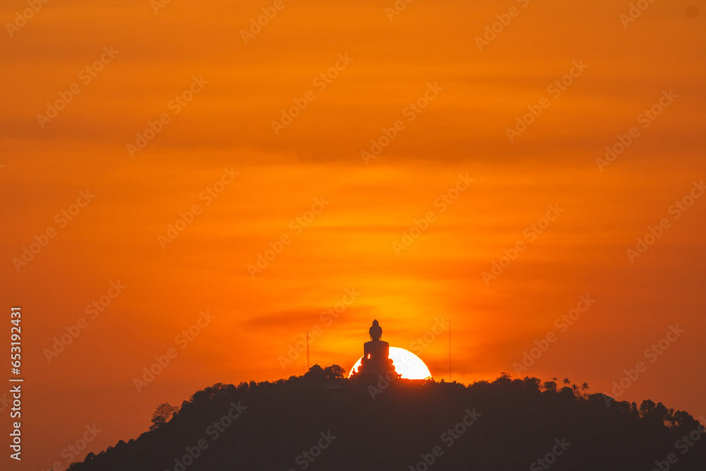 .The sun circles in the orange sky behind the Big Buddha..Amazing Phuket big Buddha in circle of the sun in yellow sky..The beauty of the statue fits perfectly with the charming nature.