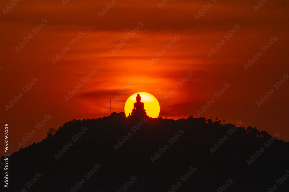 The sun circles in the red sky behind the Big Buddha..Amazing Phuket big Buddha in circle of the sun in red sky..The beauty of the statue fits perfectly with the charming nature. .red sky background