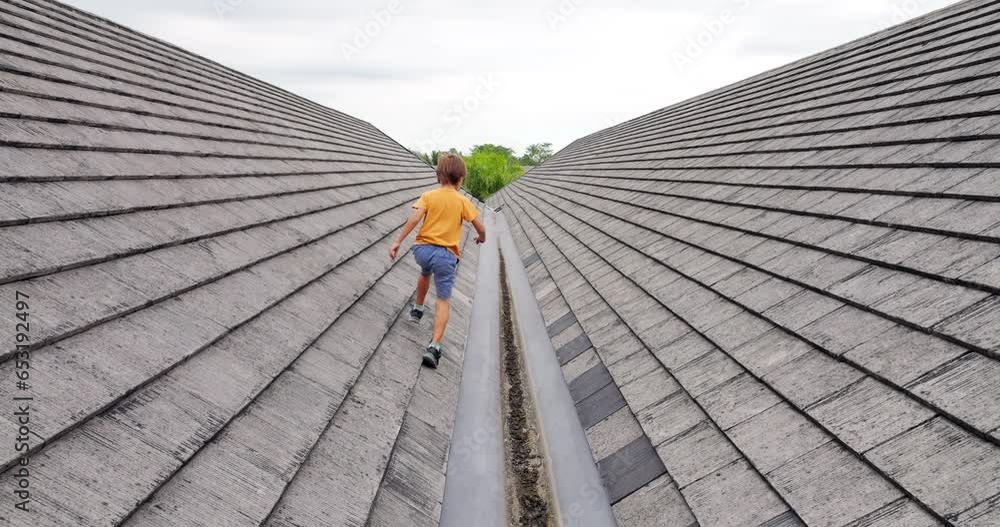 Young boy fearlessly runs, jumps, and explores rooftop, displaying