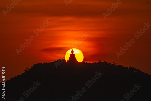 The sun circles in the red sky behind the Big Buddha..Amazing Phuket big Buddha in circle of the sun in red sky..The beauty of the statue fits perfectly with the charming nature. .red sky background