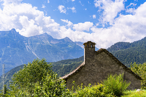 A traditional rural architecture style house built of rocks from the mountain in a beautiful alpine valley in summer, Piemonte (Piedmont), Northern Italy photo