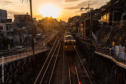 View from a railway bridge with a yellow Japanese train approaching during sunset, Onomichi, Honshu, Japan photo