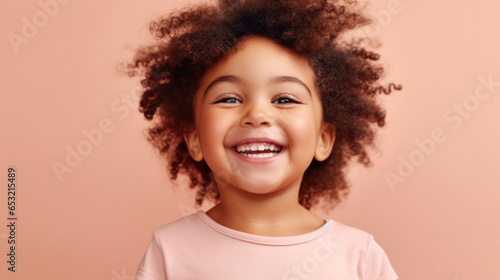 Cheerful little girl against a light beige-pink background. © iuricazac