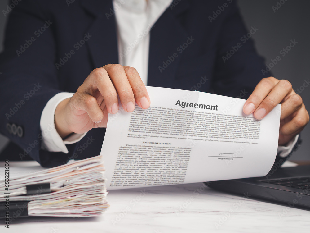 Businessman in a suit is tearing up an agreement while sitting at the table in the office. Businessman in a suit is tearing up an agreement while sitting at the table in the office.