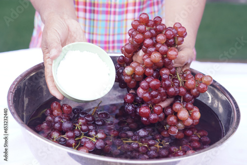 Fotografie Woman hands wash grape fruits, using baking soda powder