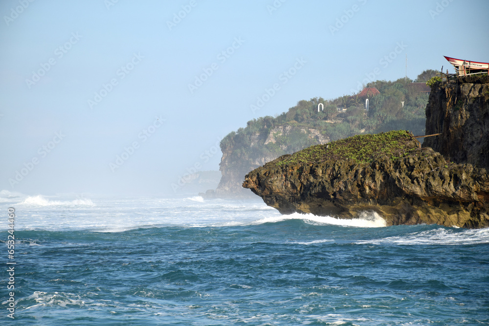 Beach waves on a sunny morning with coastal cliffs blocking the waves