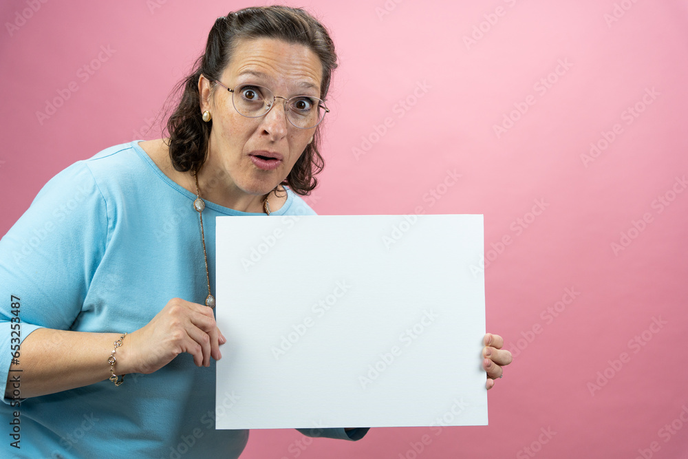 Mature Businesswoman in Blue Blouse on Colored Background holding a sign with room for copy Mature Businesswoman in Blue Blouse on Colored Background holding a sign with room for copy