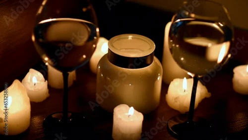 Two glasses of white wine and candles in the dark. The wind blows out the candles. Close-up. Romantic dinner