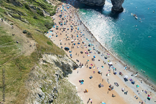 Aerial View of Many People are Enjoying Hot Summer Day of England at Durdle Door Beach During Their Holidays. Tourist Attraction Captured with Drone's Camera on Sep 9th, 2023, England UK