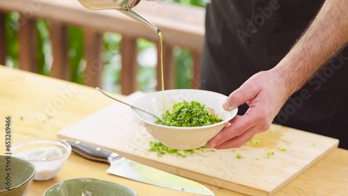 Pouring olive oil on a plate with herbs