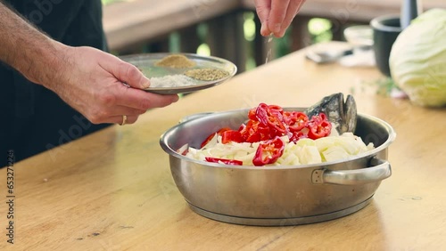 Sprinkling spices and salt on a dish with fish and vegetables