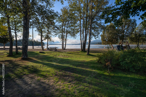 Fototapeta Naklejka Na Ścianę i Meble -  Trees shading the beach of Lake Windermere in the town of Invermere, British Columbia, Canada