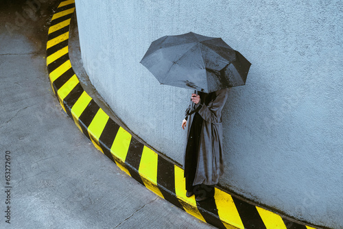 Woman holding umbrella standing near wall photo