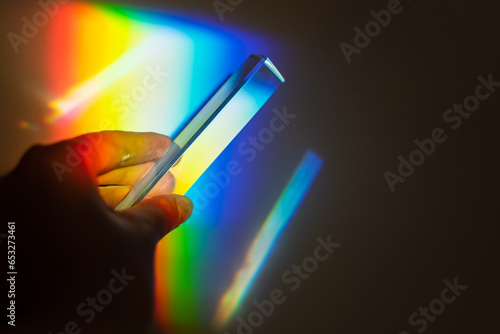 hand holding a prism rainbow effect on a wall colorful light science 