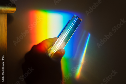 hand holding a prism rainbow effect on a wall colorful light science 