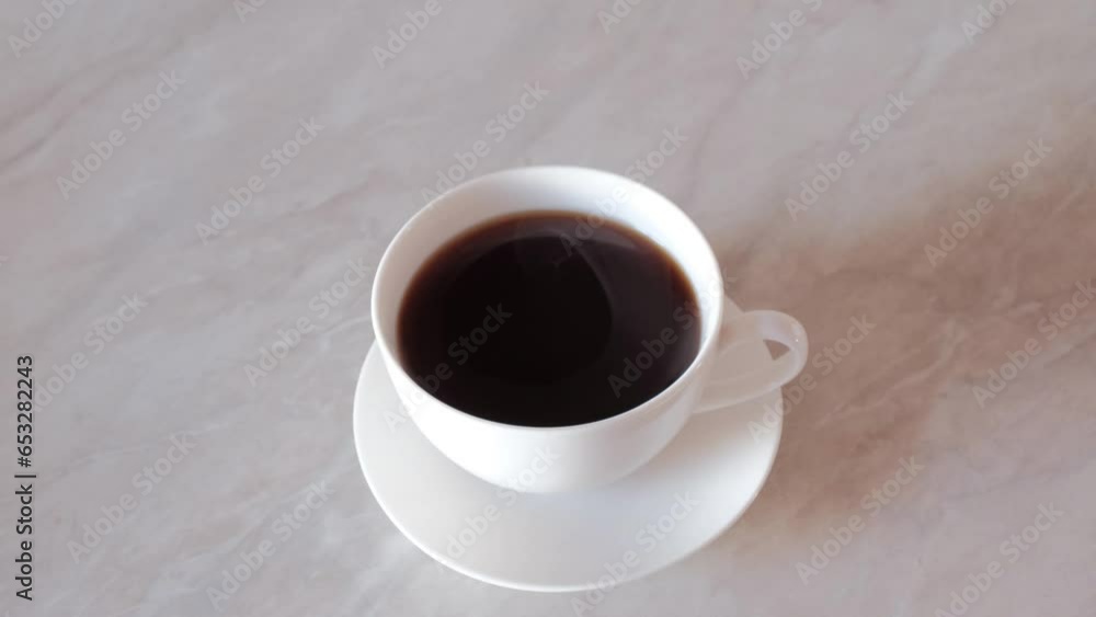 black coffee brewed in a Turk is poured into a white mug, steam rises from the coffee, a woman's hand raises the mug to drink coffee black coffee brewed in a Turk is poured into a white mug, steam rises from the coffee, a woman's hand raises the mug to drink coffee