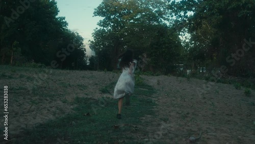 A frightened girl in a bloodstained dress runs away from her pursuer through the woods