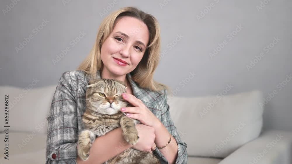 A woman holds a cat in her arms and talks about him into the frame. A woman holds a cat in her arms and talks about him into the frame.