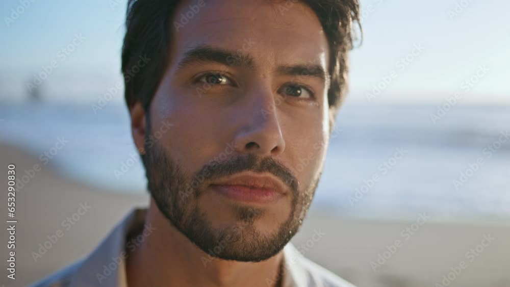 Sexy bearded man looking camera with daring smile posing on ocean coast close up Sexy bearded man looking camera with daring smile posing on ocean coast close up