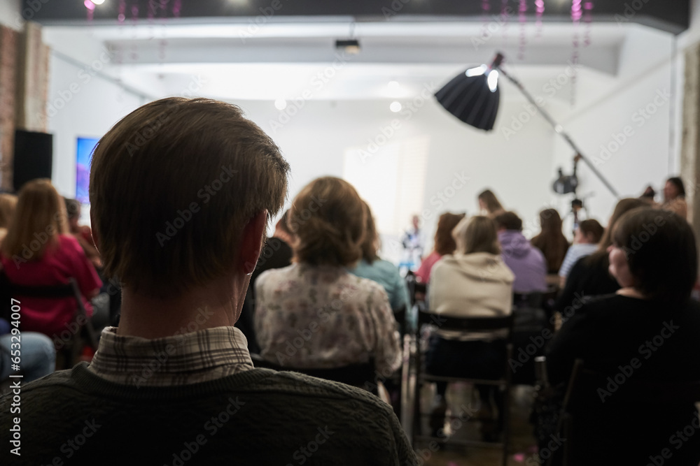 Fototapeta premium Unrecognizable people in the audience, rear view. Sitting at a lecture or meeting at the university. business and entrepreneurship or the concept of learning. High quality photo