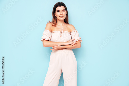 Young beautiful smiling female in trendy summer costume clothes. Carefree woman posing near blue wall in studio. Positive model having fun indoors. Cheerful and happy © halayalex