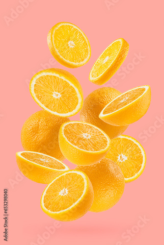 Bright oranges closeup levitation as flow  art composition. Whole  half  round slices fruits on pastel pink background  shadow. Summer fruits for advertising  design  label product  poster  card.