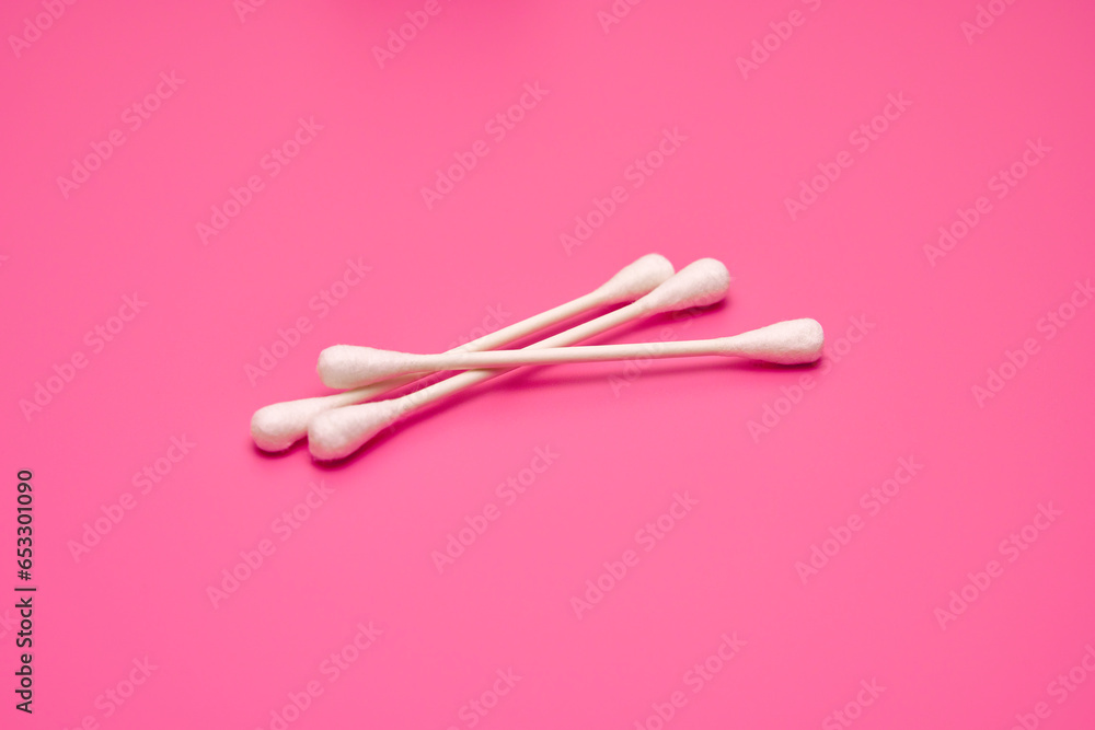 Three white cotton swabs on a pink background Three white cotton swabs on a pink background