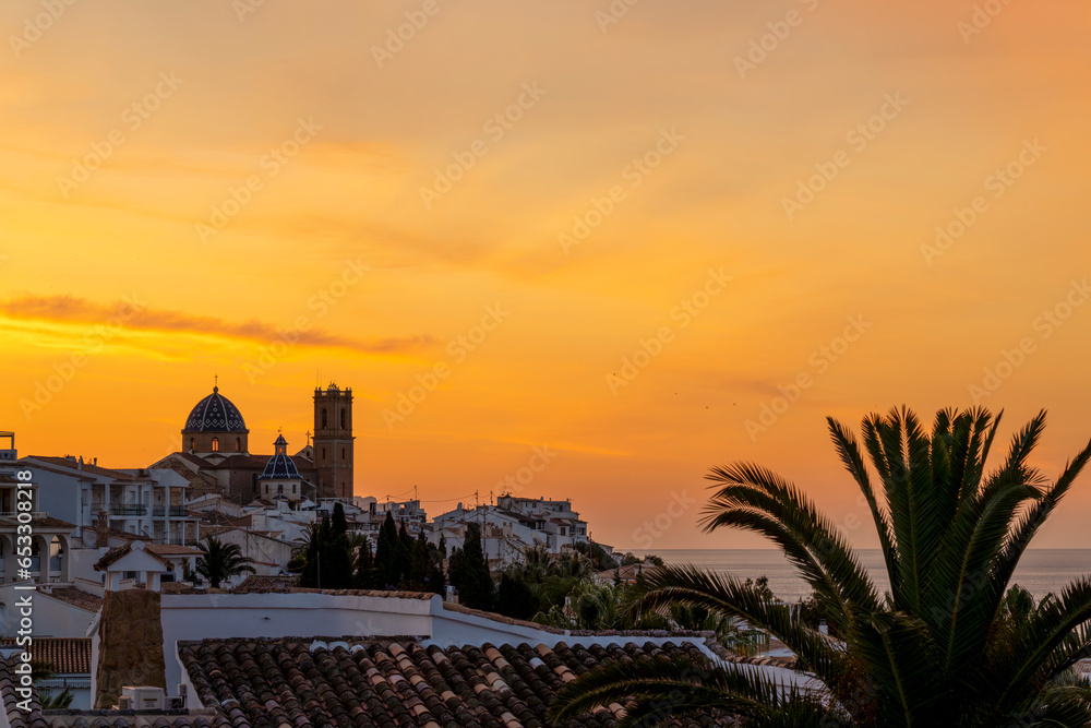 Sunrise with golden sky over the city of Altea with catholic church in the middle colled Nostra Senyora del Consol