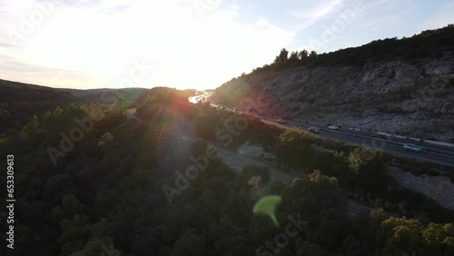 Drone shot of a highway surrounded by a forest during a sunset. Traffic is heavy on the A75 highway, south of France. photo