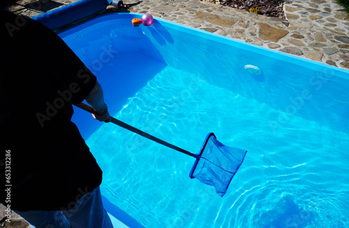 Young woman cleans swimming pool. Personnel cleaning the pool from leaves in sunny summer day. Hotel staff worker cleaning the pool. Cleaning swimming pool service. Purification with a net. Close up
