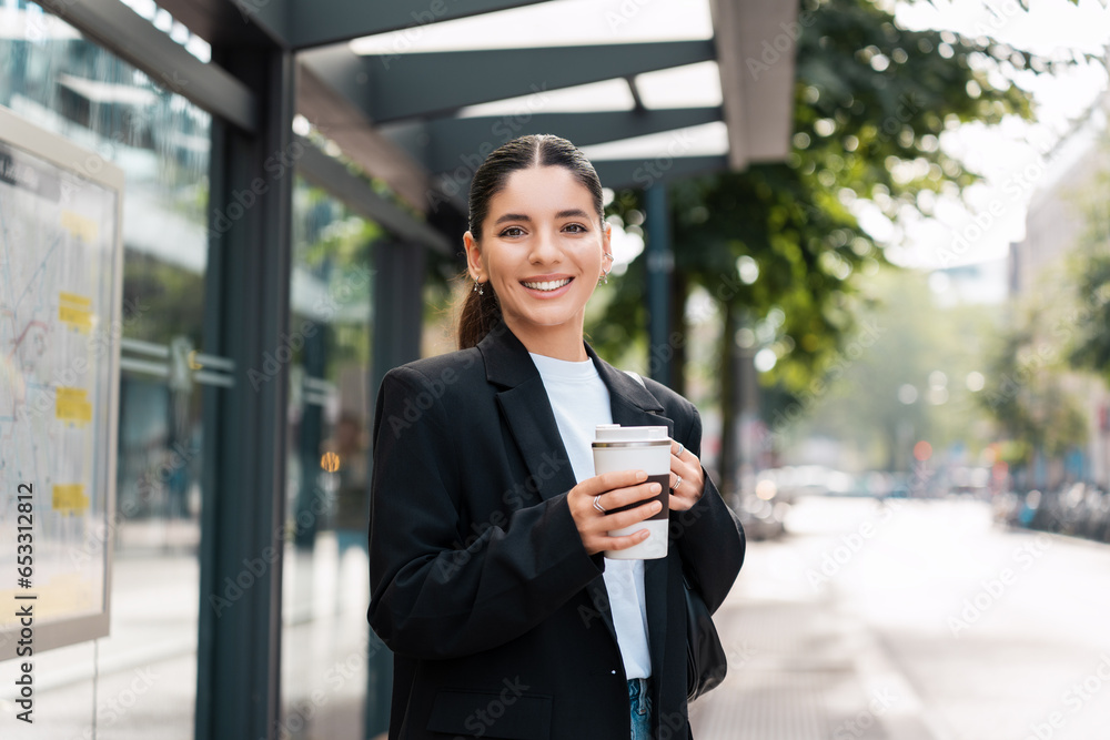 Beautiful young multiracial hispanic business woman using public transportation in city smiling and holding eco thermo cup with coffee Beautiful young multiracial hispanic business woman using public transportation in city smiling and holding eco thermo cup with coffee