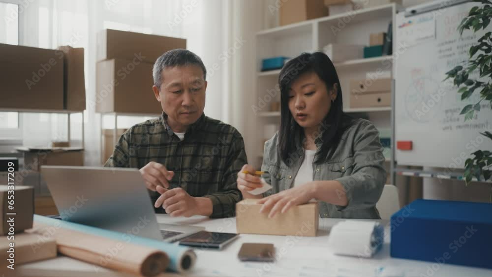 Asian small business owners processing and packing orders in office, teamwork Asian small business owners processing and packing orders in office, teamwork
