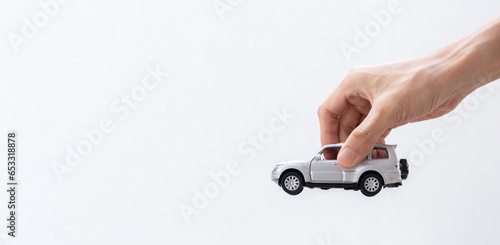 Hand holding a toy car isolated on gradient background. After some edits.
