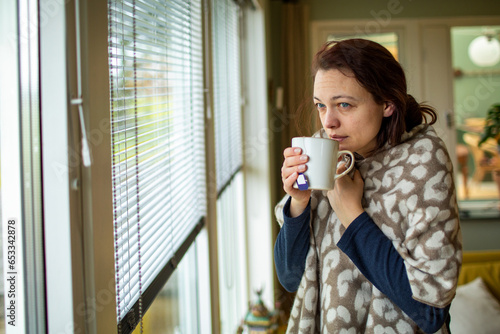 Young sick woman drinking tea to feel better at home