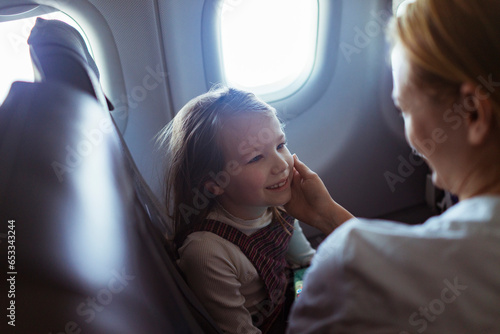 Young mother embracing her daughter on their flight photo