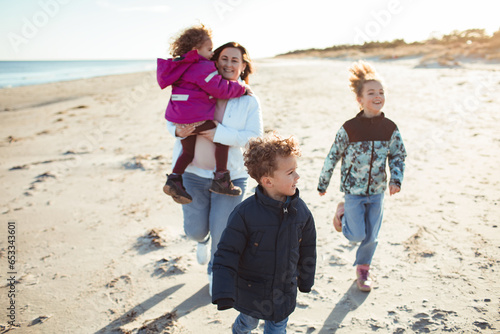 Young blended family walking and having fun on the beach together photo