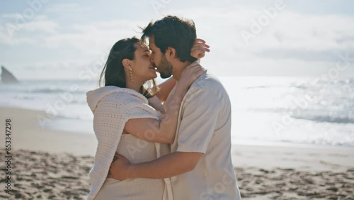Affectionate expectant parents kissing seacoast enjoying romantic date close up.