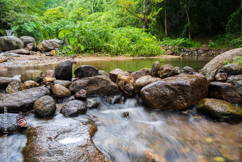 A small waterfall with many rocks in the stream. Surrounded by trees in the mountain forest.