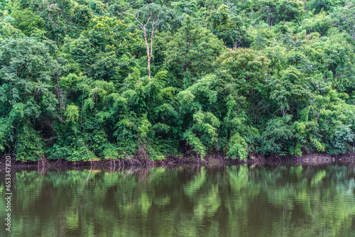 A small lake in Thailand surrounded by mountains with lush green forest and mist.