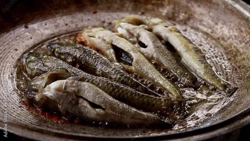 Close up of small herring or tamban frying in an iron skillet, a candid authentic moment of the