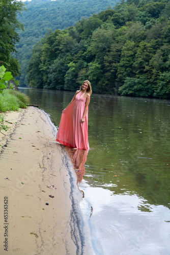 Beautiful woman in pink dress along lake shoreline