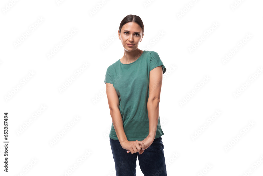 Fototapeta premium young black-haired woman in a green basic t-shirt looking at the camera on a white background with copy space